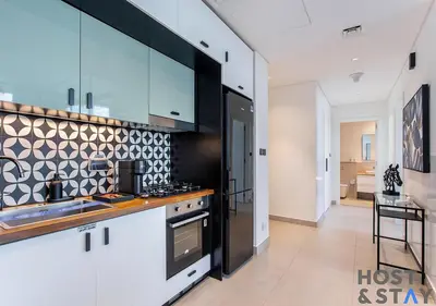 a kitchen with white and black cabinets and a counter at Upgraded 2BR In Dubai Hills in Dubai