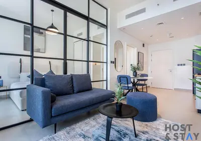 a living room with a blue couch and a table at Modern 1bed Haven in Dubai Hills in Dubai
