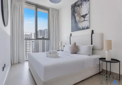 a white bedroom with a large white bed and a window at Minimalist 2BR in Dubai Hills in Dubai
