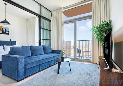 a living room with a blue couch and a balcony at Amazing 2BR in Collective 2 in Dubai