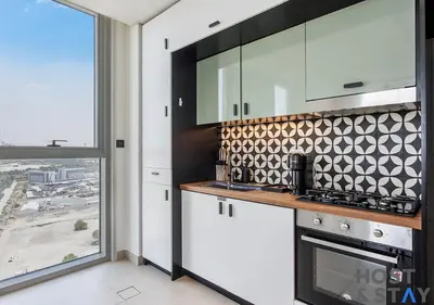 a kitchen with white cabinets and a large window at Amazing 2BR in Collective 2 in Dubai