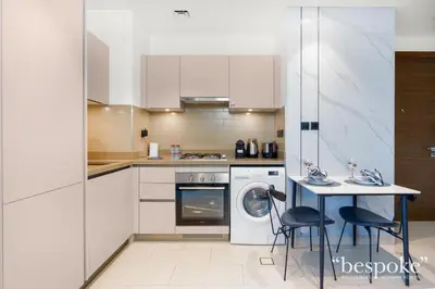 a kitchen with white cabinets and a table with chairs at Bespoke Holiday Homes - Sobha Creek Vistas Reserve in Dubai