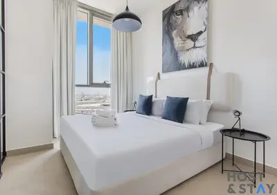 a bedroom with a large white bed with a lion painting on the wall at Stunning 1BR in Dubai Hills in Dubai
