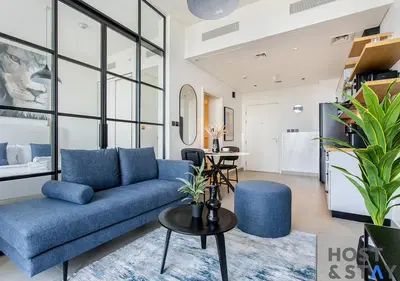 a living room with a blue couch and a table at Stunning 1BR in Dubai Hills in Dubai