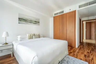 a white bedroom with a bed and a wooden cabinet at GuestReady - Home away from home in JLT in Dubai