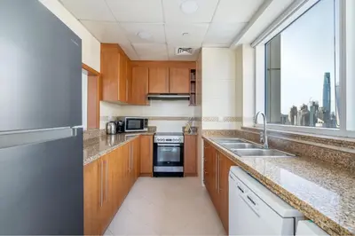 a kitchen with wooden cabinets and a sink and a window at GuestReady - Home away from home in JLT in Dubai