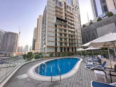 a swimming pool with chairs and umbrellas on a building at AWS Holiday Homes - In the Heart of Downtown in Dubai