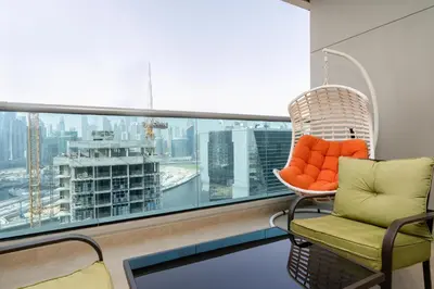 an orange chair in a room with a large window at Elite Residence - Business Bay in Dubai