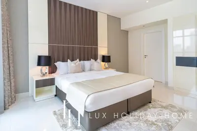 a bedroom with a large white bed with two lamps at LUX The Bays Edge Canal View Suite in Dubai