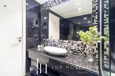a bathroom with a sink and a vase of flowers on a counter at LUX The Bays Edge Canal View Suite in Dubai