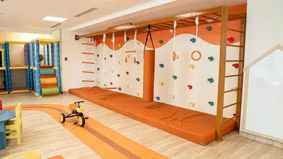a climbing wall in a kids room with a couch at Medore Brand New 1 and a half Bedroom apartment in Dubai