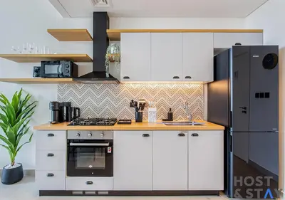 a kitchen with white cabinets and a black refrigerator at Lux 1BR Near Dubai Hills Mall in Dubai