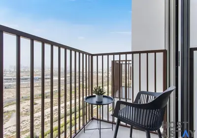 a balcony with a chair and a table with a view at Lux 1BR Near Dubai Hills Mall in Dubai