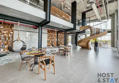 a library with tables and chairs and a staircase at Lux 1BR Near Dubai Hills Mall in Dubai