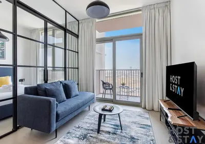 a living room with a blue couch and a tv at Lux 1BR Near Dubai Hills Mall in Dubai