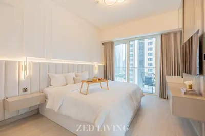 a white bedroom with a bed with a table on it at Me Do Re - Luxury Living 1 BR with Panoramic View - Zed Living in Dubai