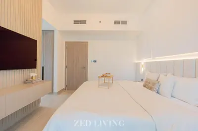 a bedroom with a large white bed and a tv at Me Do Re - Luxury Living 1 BR with Panoramic View - Zed Living in Dubai