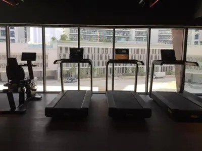 a gym with three treadmills in front of a window at #140 Elegant 1BR with Burj Khalifa View in Business Bay in Dubai