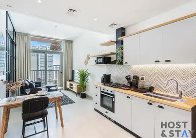 a kitchen with white cabinets and a table and a dining room at Elegant 1BR In Collective, Dubai Hills in Dubai