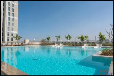 a large swimming pool with blue water in a building at Amazing 1BR in Collective2, Dubai Hills in Dubai
