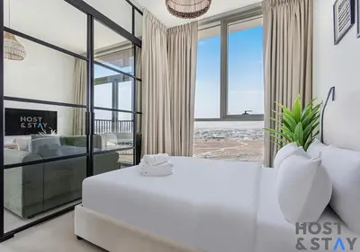 a bedroom with a white bed and a large window at Modern 2BR Gem In Dubai Hills in Dubai