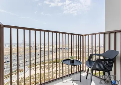 a balcony with a chair and a table on it at Modern 2BR Gem In Dubai Hills in Dubai