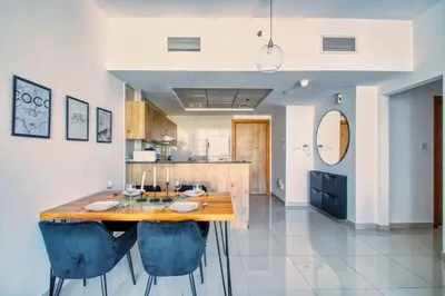 a kitchen and dining room with a wooden table and blue chairs at ShoresInn - Spacious unit with Dubai Marina View in Dubai