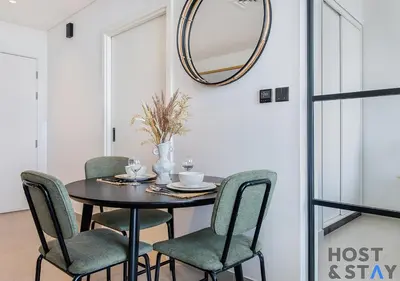 a dining room table with chairs and a mirror at Stylish 1BR Apt In Collective 2 in Dubai