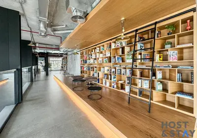 a library with wooden shelves and two chairs and books at Stylish 1BR Apt In Collective 2 in Dubai