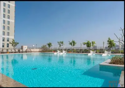 a large swimming pool with white chairs and blue water at Stylish 1BR Apt In Collective 2 in Dubai
