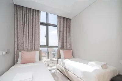 two beds in a room with a large window at Aykon City 2 bedroom Burj view in Dubai