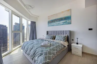 a bedroom with a bed and large windows at High Floor Brand New Apartment - 34 in Dubai