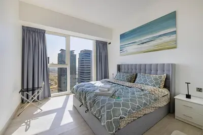 a bedroom with a bed and a large window at High Floor Brand New Apartment - 34 in Dubai