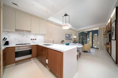 a kitchen with a white counter and a dining room at Address Emaar Flagship Burj Khalifa Fountain view UPSCALE in Dubai
