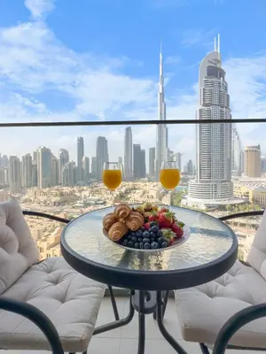 a plate of food on a table with two glasses of orange juice at Luxury - Fountain Show & Burj Khalifa View - 2 BR - 3 beds in Dubai