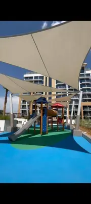a playground with benches and a slide in front of a building at Lovely Studio, Azizi Riviera in Dubai