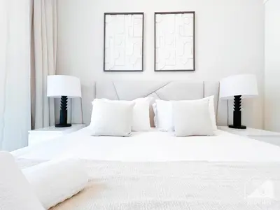 a white bedroom with white pillows and two lamps at Luxury Burj Crown Downtown Balcony & View in Dubai