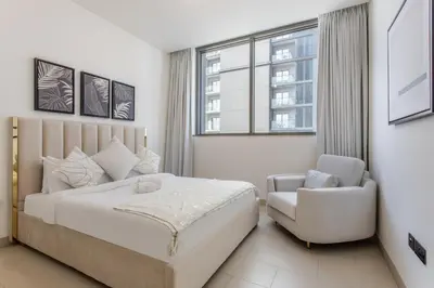 a bedroom with a bed and a chair and a window at STAY BY LATINEM Luxury 2BR Holiday Home CVR B1705 near Burj Khalifa in Dubai