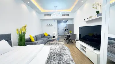 a white bedroom with a large television and a couch at Dubai Marina - Modern Classic Studio Apartment in Dubai