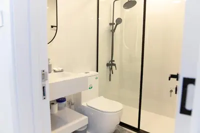 a white bathroom with a toilet and a shower at Dubai Marina - Modern Classic Studio Apartment in Dubai