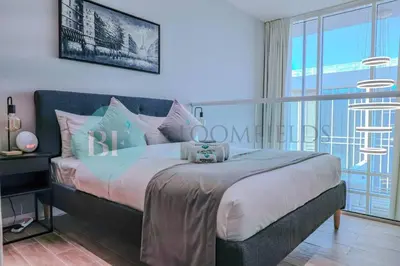 a bedroom with a bed and a large window at Bloomfields Cozy 1br Townhouse Life Style City in Nadd Shubayḩ