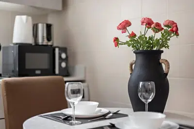 a black vase with red flowers on a table with glasses at Studio -DEC Towers T2 - Near Marina Beach in Dubai