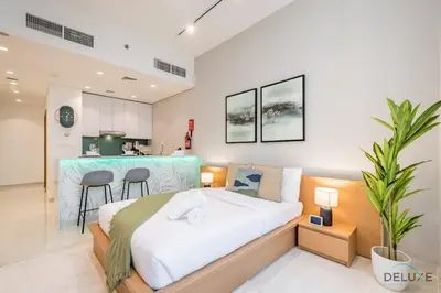 a bedroom with a large bed and a kitchen at Stylish Studio Apartment in Blue Wave Tower, Dubailand by Deluxe Holiday Homes in Dubai