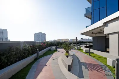 a walkway with benches and plants on a building at Stylish Studio Apartment in Blue Wave Tower, Dubailand by Deluxe Holiday Homes in Dubai