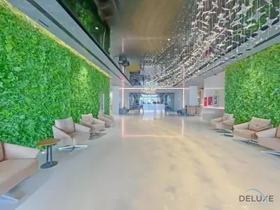 a large room with a green wall and chairs at Stylish Studio Apartment in Blue Wave Tower, Dubailand by Deluxe Holiday Homes in Dubai