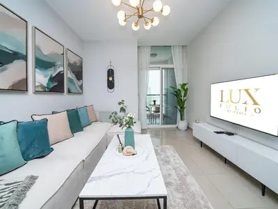 a living room with a white couch and a tv at Sleek 2 Bed in Sports City in Dubai