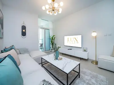 a living room with a white couch and a table at Sleek 2 Bed in Sports City in Dubai