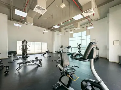 a gym with several treadmills and elliptical machines at Sleek 2 Bed in Sports City in Dubai