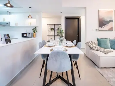 a kitchen and living room with a white table and chairs at Sleek 2 Bed in Sports City in Dubai