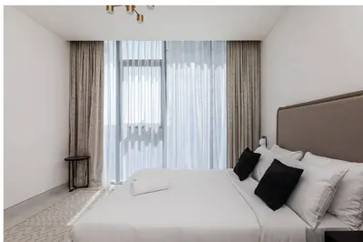 a white bed in a room with a large window at Spacious 1 BR Lagoon in Dubai